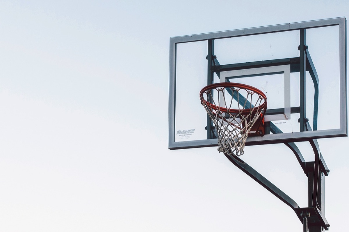 Een basketbalring met een net op een buitenveld