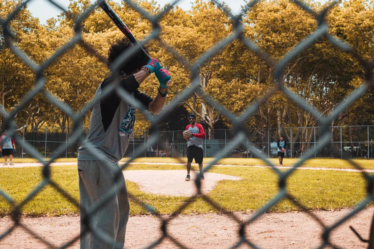 Casual baseball game at a New York City park, showcasing players in action and vibrant autumn scenery.