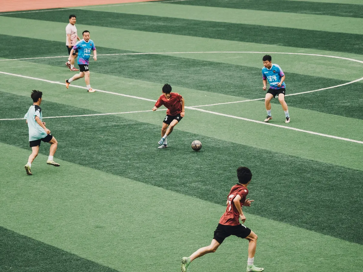 Action shot of teenagers playing soccer on a green sports field.