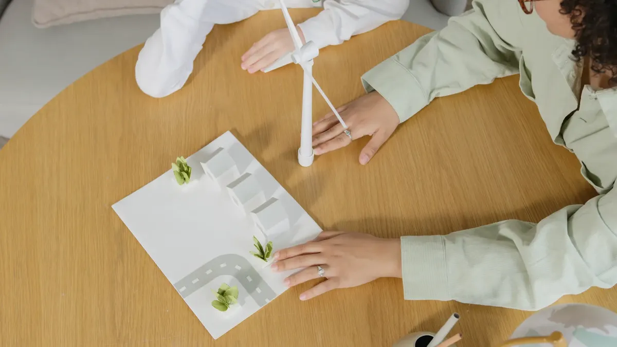 Children playing with a wind turbine model, learning sustainable energy concepts indoors.