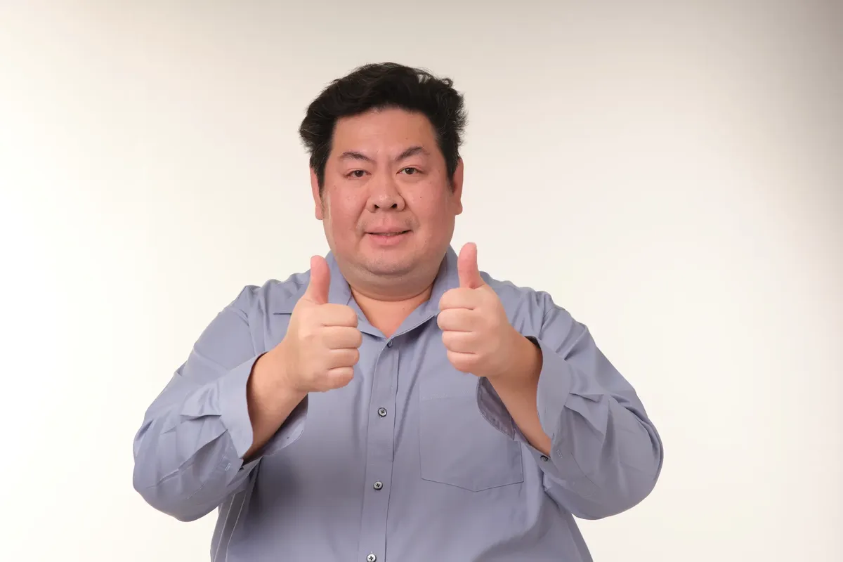 A cheerful adult man in a blue shirt giving a double thumbs up. Perfect for concepts of approval and positivity.